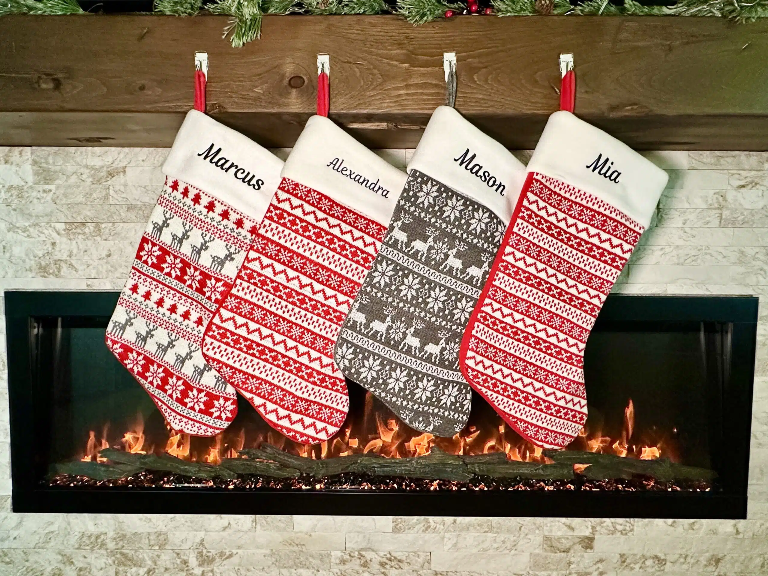 Personalized Christmas stockings in red, green and white hanging on a mantel with embroidered names